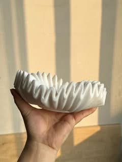 White fluted marble fruit bowl held by hand, elegant home decor.